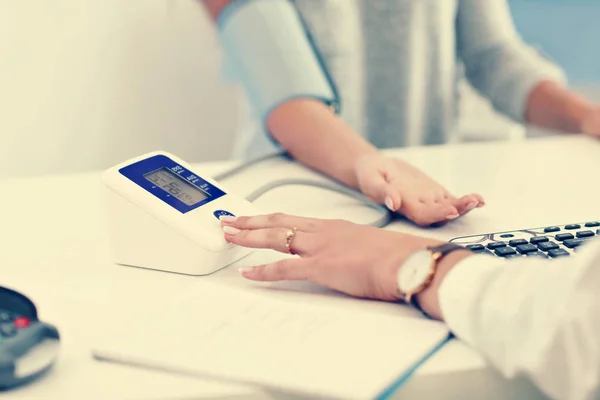 Volwassen vrouw met bloeddruk test tijdens bezoek bij vrouwelijke artsen kantoor — Stockfoto