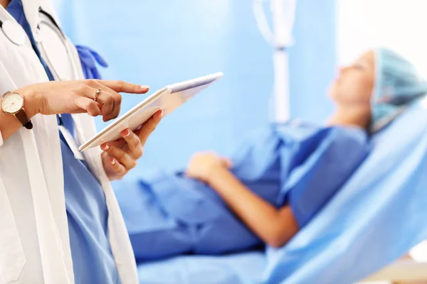 Lääkäri seisoo tabletin kanssa naispotilaan edessä sairaalassa — kuvapankkivalokuva