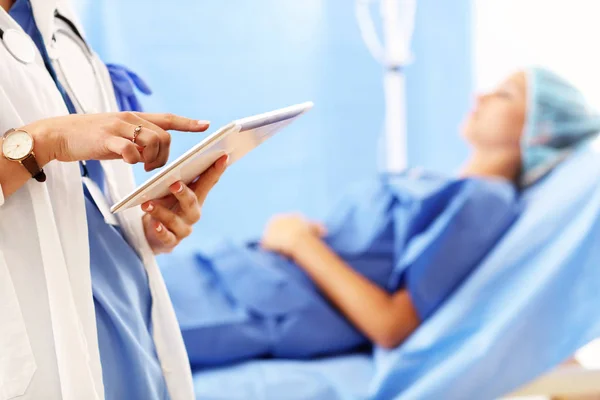 Arzt steht mit Tablette vor Patientin im Krankenhaus — Stockfoto