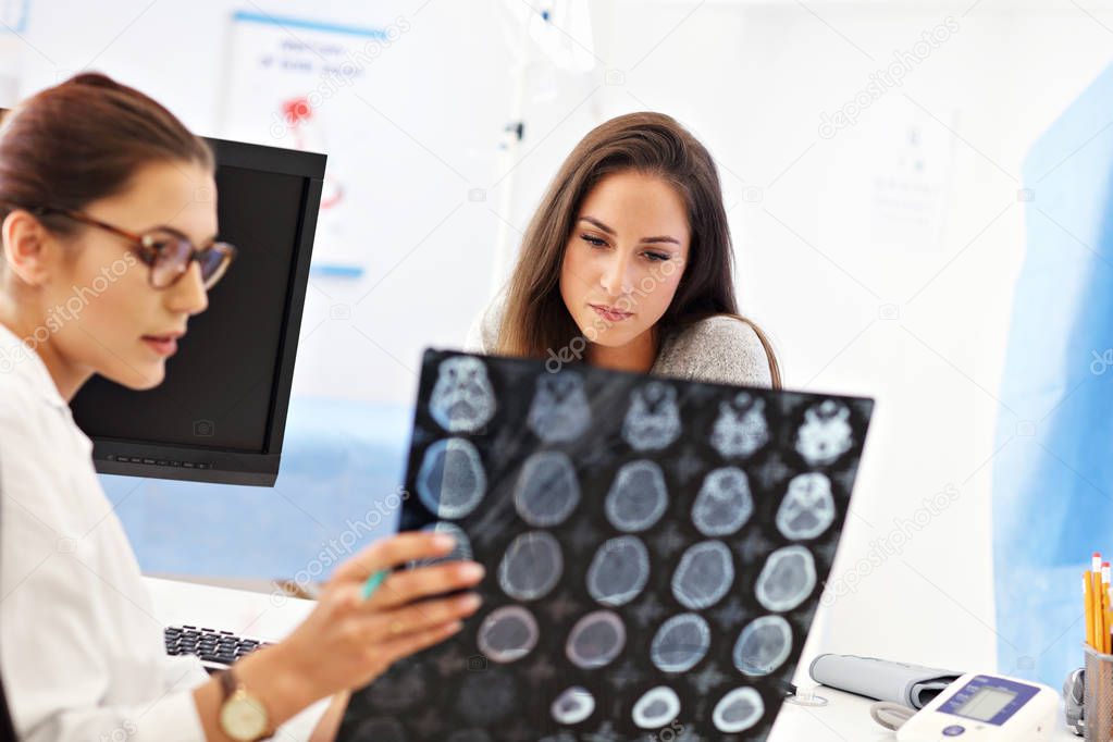 Adult woman discussing x-ray results during visit at female doctors office