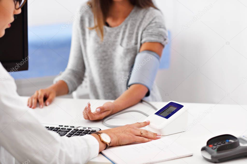 Adult woman having blood pressure test during visit at female doctors office