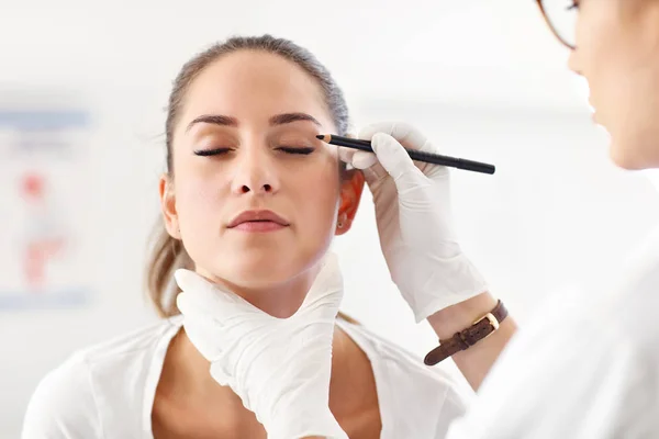 Plastic surgeon making marks on patients body — Stock Photo, Image