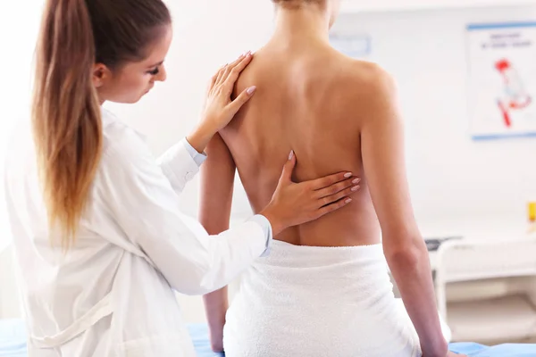 Fisioterapeuta femenina ayudando a una paciente con problemas de espalda en la clínica —  Fotos de Stock