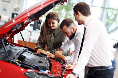 Kendine güvenen genç satıcı genç çekici sahiplerine araba özellikleri açıklayan