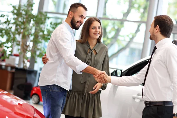 Jovem casal escolhendo carro no showroom — Fotografia de Stock