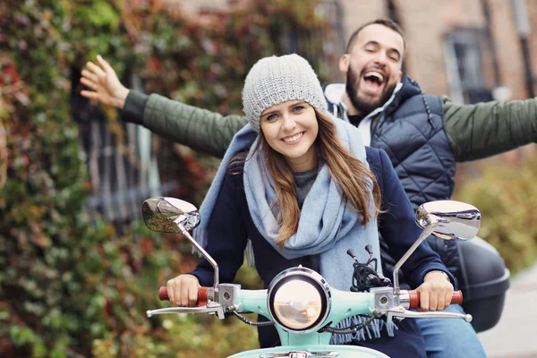 Mooie jonge paar glimlachen tijdens het rijden van scooter in stad in de herfst — Stockfoto