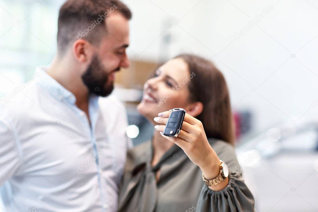 Adult couple choosing new car in showroom