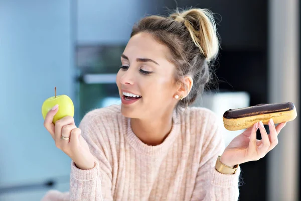 Mujer eligiendo entre manzana y eclair — Foto de Stock