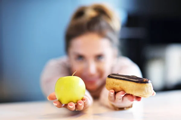 Mulher escolhendo entre maçã e eclair — Fotografia de Stock