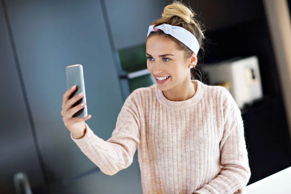 Gelukkige vrouw texting in de keuken — Stockfoto