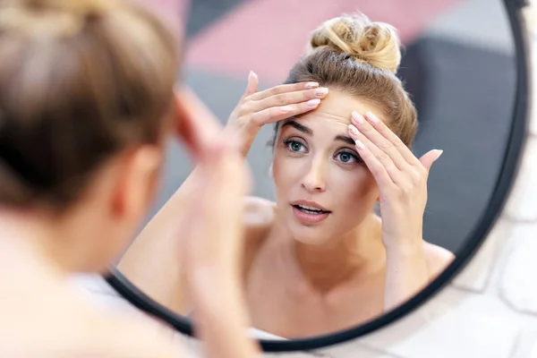 Молода жінка чистить обличчя у дзеркалі ванної кімнати — стокове фото