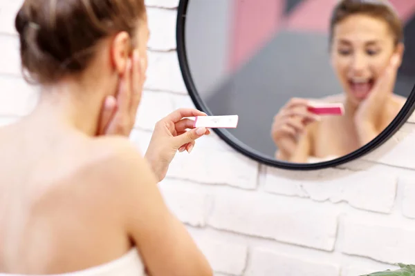 Mujer joven con prueba de embarazo en el baño —  Fotos de Stock