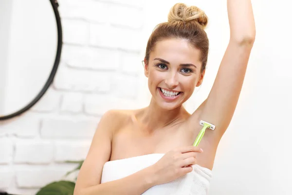 Junge Frau rasiert Achseln im Badezimmer — Stockfoto