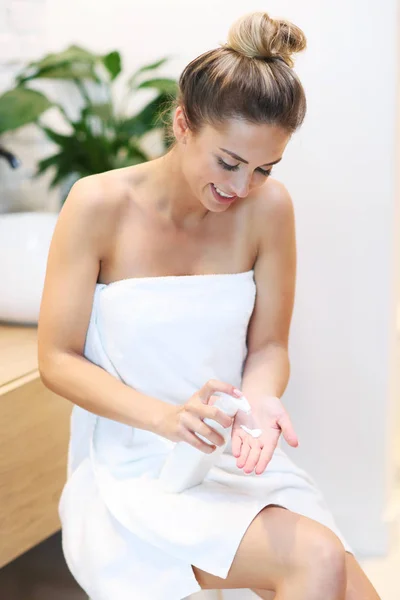 Jovem mulher usando cosméticos no banheiro — Fotografia de Stock