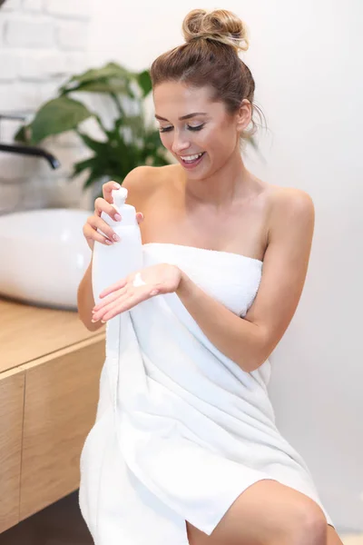 Young woman using cosmetics in bathroom — Stock Photo, Image