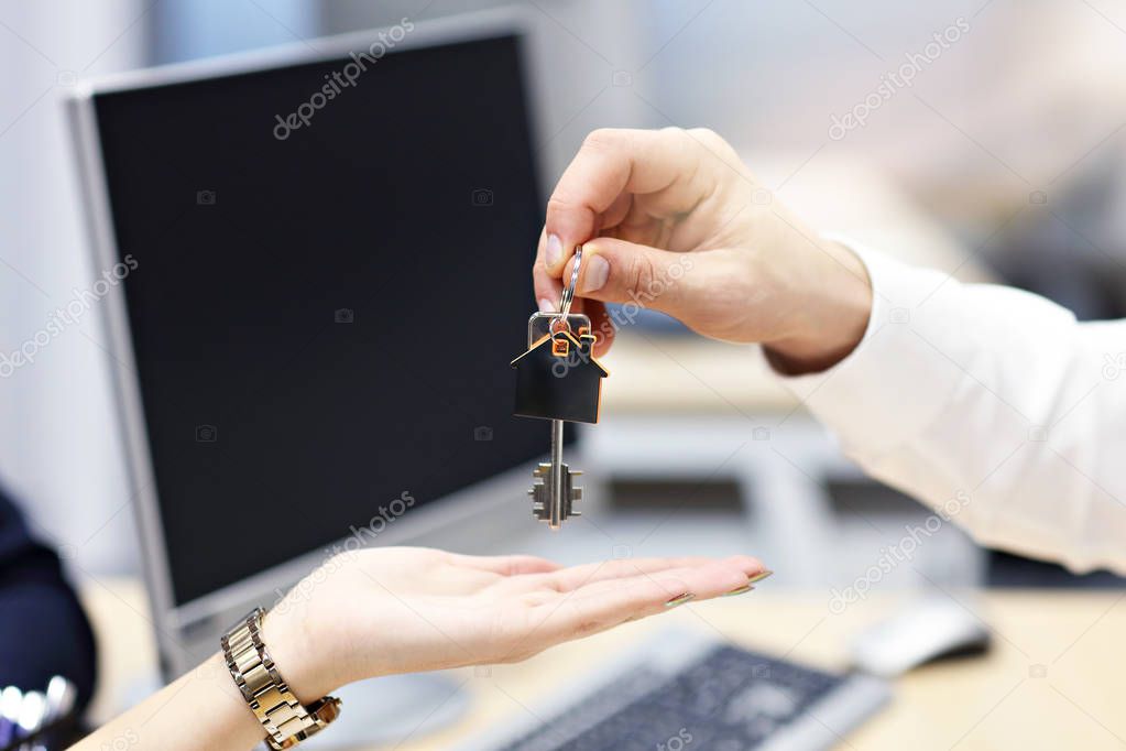 Midsection of real estate agent and buyer hands with keys