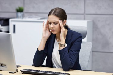 Close up portrait of businesswoman with headache at workplace