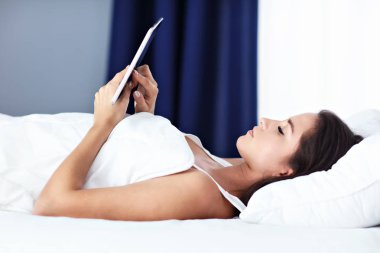 Genç güzel kadın yatakta smartphone ile dinlenme