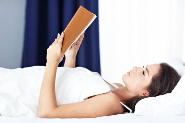 Genç güzel kadın yatakta kitap ile dinlenme