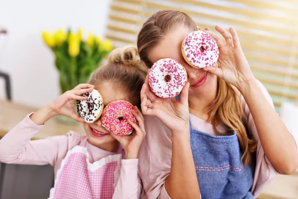 Klein meisje en haar moeder in schorten plezier in de keuken — Stockfoto