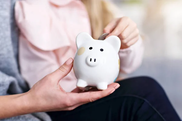 Young girl and her mother with piggybank sitting at table — Stock Photo, Image