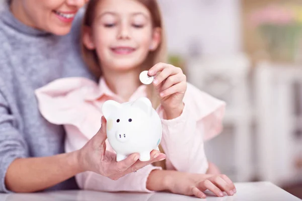 若い女の子とのテーブルに座って piggybank を彼女の母 — ストック写真