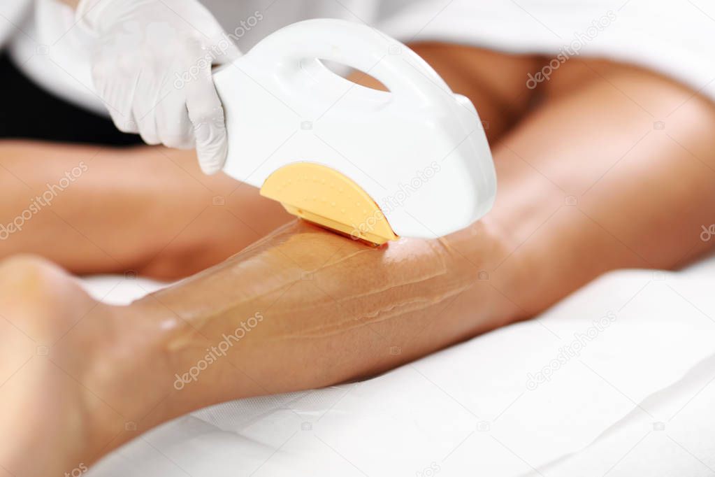 Beautician Giving Epilation Laser Treatment To Woman On Legs