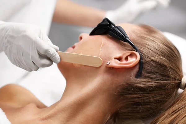 Esteticista dando tratamento a laser de compilação para a mulher no rosto — Fotografia de Stock