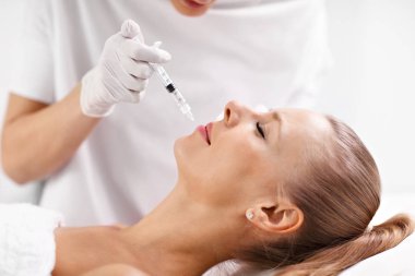 Kadın dudaklarında botox enjeksiyon yapma güzellik uzmanı el yakın çekim