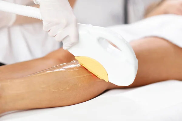 Esteticista dando tratamento a laser de compilação para a mulher nas pernas — Fotografia de Stock