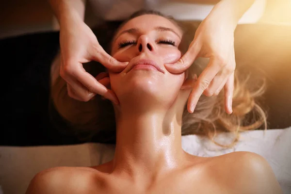 Happy woman having face massage in spa salon — Φωτογραφία Αρχείου