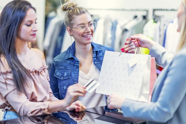 Foto del grupo de amigos felices comprando ropa en el centro comercial —  Fotos de Stock