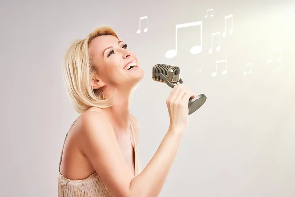 Hübsche Frau singt vor grauem Hintergrund — Stockfoto