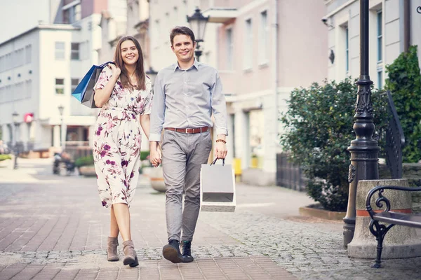 Retrato de pareja feliz con bolsas de compras en la ciudad sonriendo y abrazando . —  Fotos de Stock