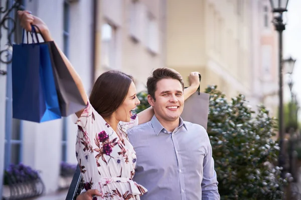 Retrato de casal feliz com sacos de compras na cidade sorrindo e abraçando . — Fotografia de Stock