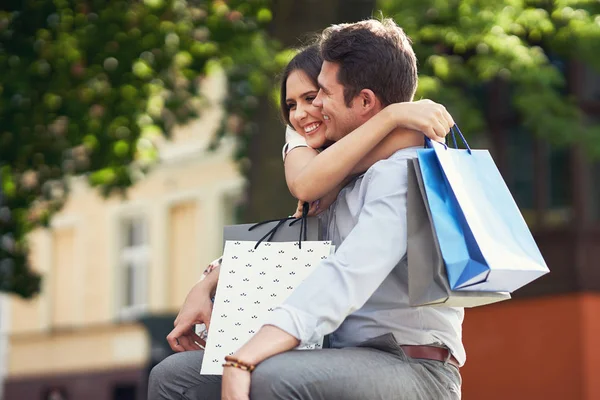 Retrato de pareja feliz con bolsas de compras en la ciudad sonriendo y abrazando . — Foto de Stock