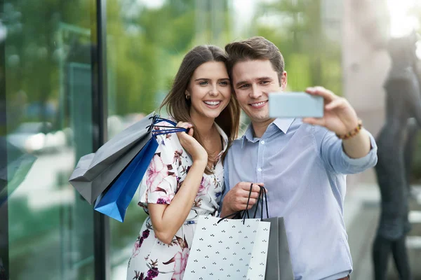 Portré boldog pár a bevásárlótáskák a városban mosolyogva és megölése. — Stock Fotó