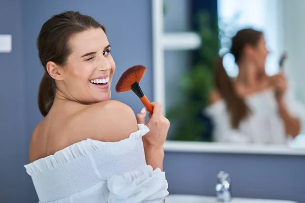 Красива брюнетка жінка застосовує вибір у ванній — стокове фото