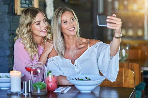 Två tjej vänner som äter lunch i restaurang och använder smartphone — Stockfoto