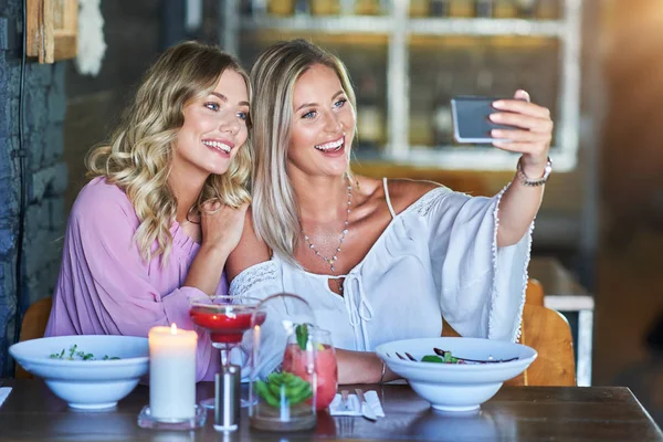 To venninner som spiser lunsj på restaurant og bruker smarttelefon – stockfoto