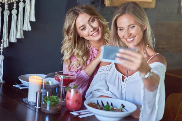 Deux amies déjeunent au restaurant et utilisent un smartphone — Photo