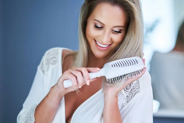 Glückliche Frau beim Haareputzen im Badezimmer — Stockfoto