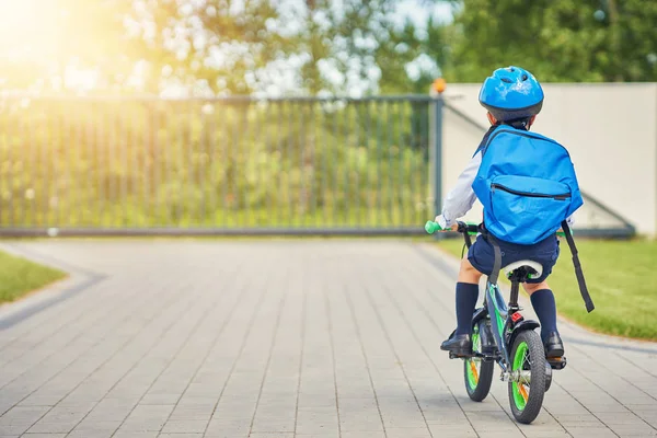 バックパック付き安全ヘルメットに乗って自転車の男子生徒 — ストック写真