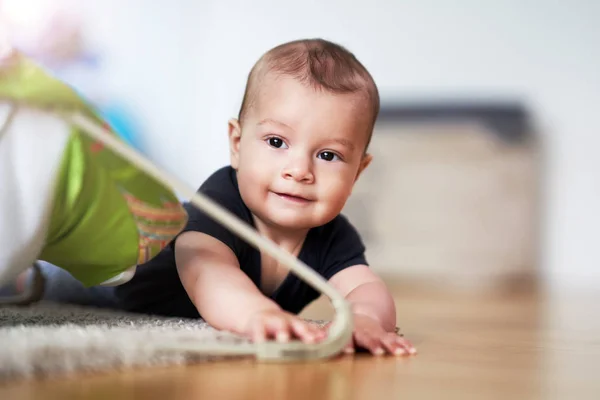 Милий усміхнений хлопчик плаче на підлозі у вітальні — стокове фото