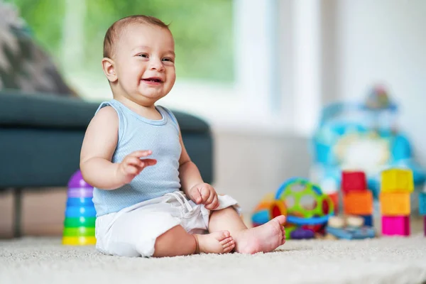 Cute smiling baby boy sitting on floor in living room — Stock Photo, Image