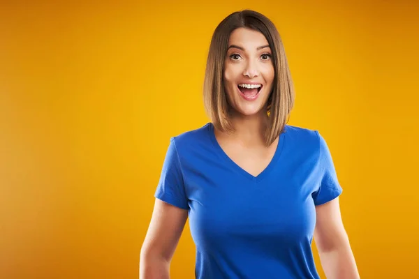 Primer plano de la mujer en camiseta azul mirando a la cámara sobre fondo amarillo —  Fotos de Stock