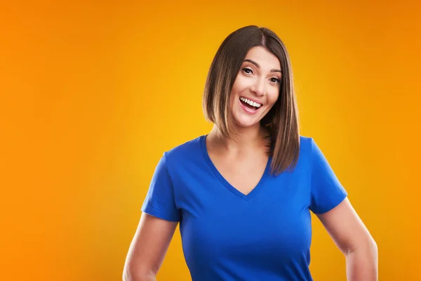 Närbild av kvinna i blå t-shirt tittar på kamera över gul bakgrund — Stockfoto