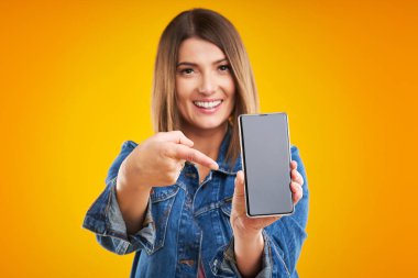 Sarı arka plan üzerinde akıllı telefon ile denim ceketli kadının yakın çekim