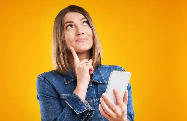 Närbild av kvinna i jeansjacka med smartphone över gul bakgrund — Stockfoto