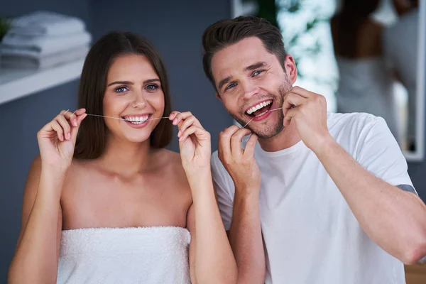 Porträt eines glücklichen jungen Paares mit Zahnseide im Badezimmer — Stockfoto